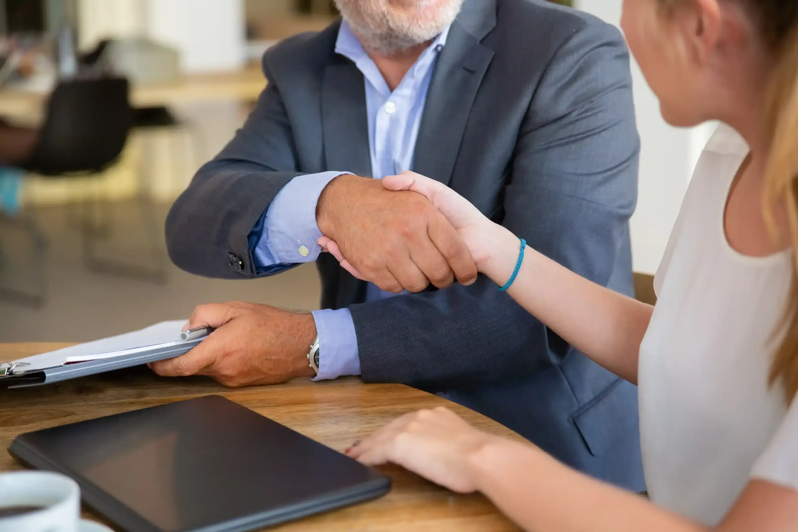 Conseiller juridique mature rencontrant un jeune client en espace de co-working, tenant des documents et se serrant la main