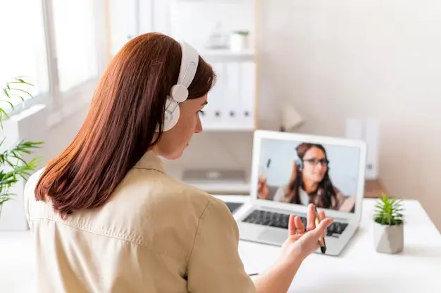 Femme au travail participant à un appel vidéo depuis son ordinateur portable, en pleine discussion professionnelle.
