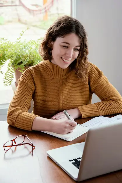 Jeune femme suivant un cours en ligne sur son ordinateur, concentrée et engagée dans son apprentissage.