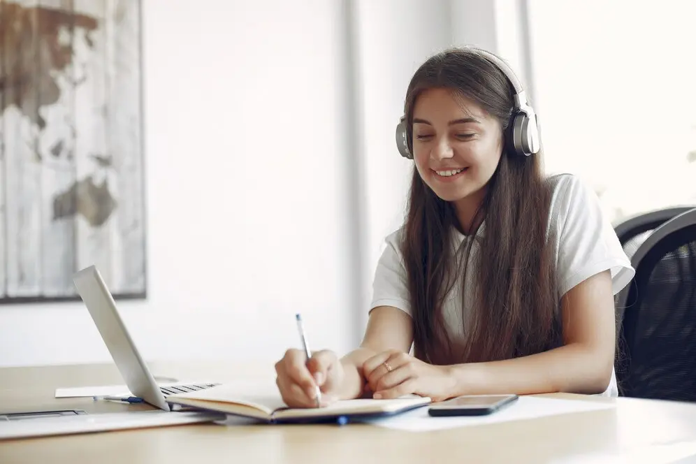 Jeune étudiant assis à une table, utilisant son ordinateur portable pour ses études.