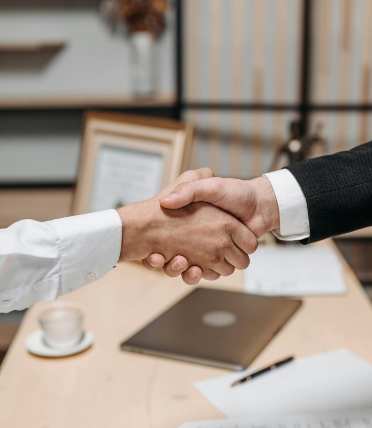 Deux personnes en tenue professionnelle se serrent la main dans un cadre de bureau, illustrant un partenariat ou un engagement commun.