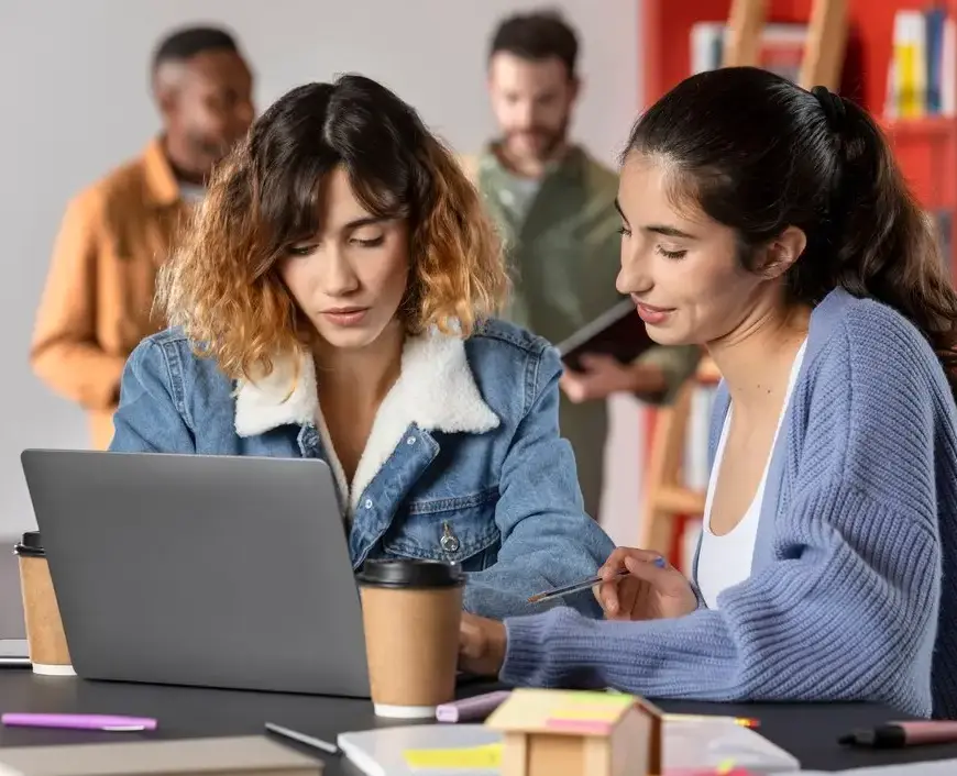 Amis apprenant ensemble, prenant des notes sur un ordinateur portable pendant une session d'étude.
