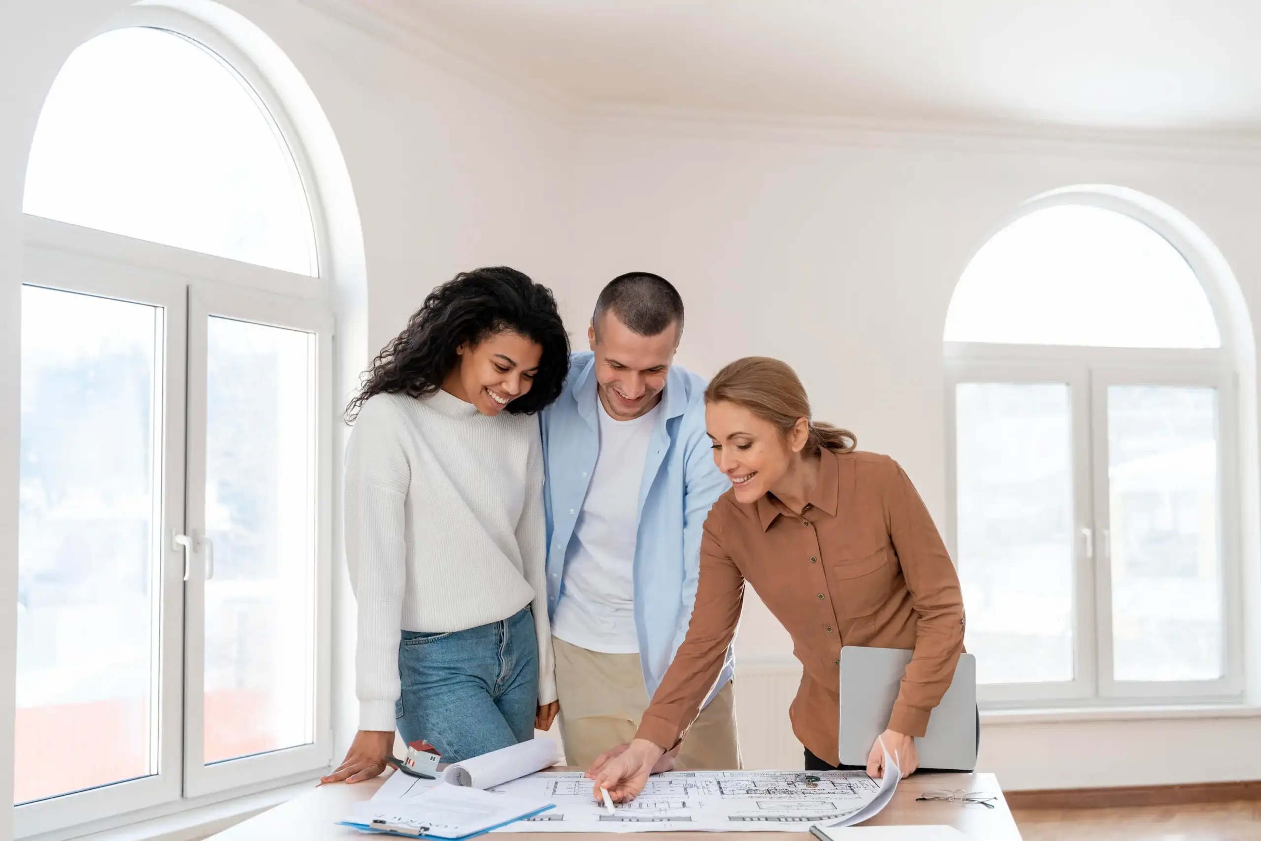 Agente immobilière présentant un plan de maison à un couple, discutant des options pour leur futur chez-soi